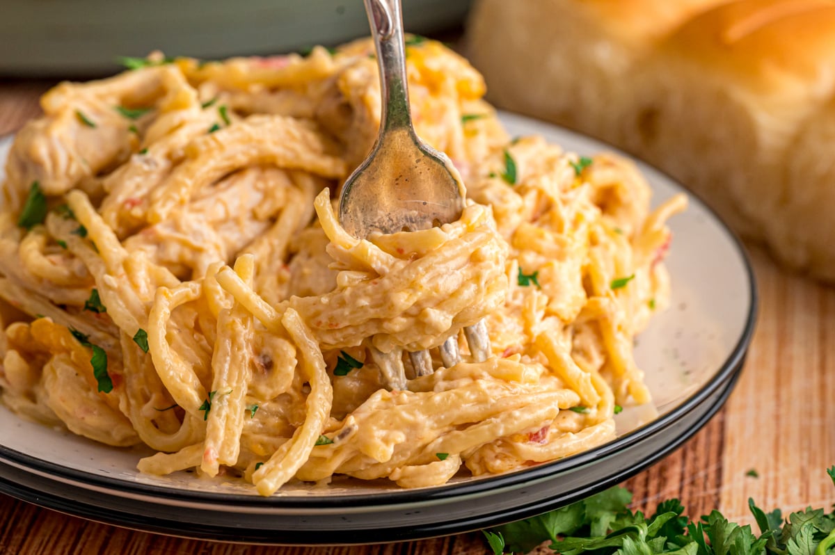 A fork twirling spaghetti and chicken on a plate.