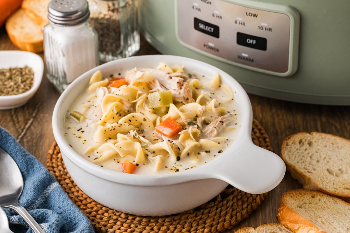 A serving of creamy chicken noodle soup in a white bowl.