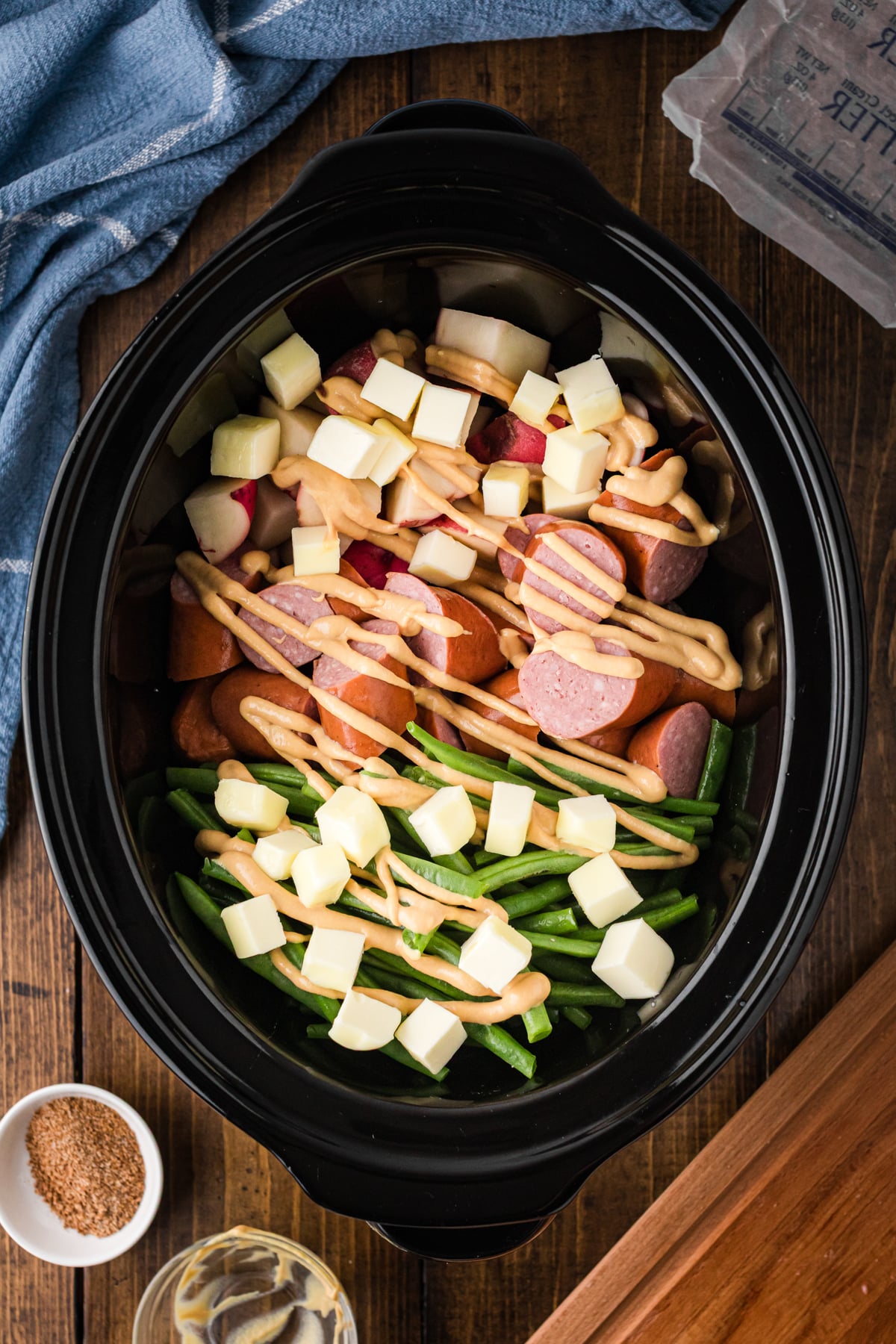 Cubed butter on top of ingredients in a slow cooker.