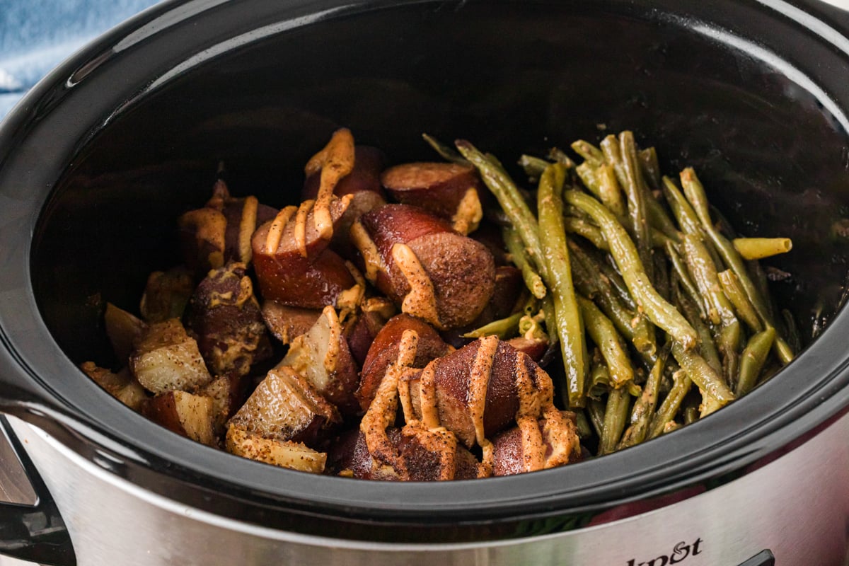 Kielbasa, green beans, and potatoes in a crockpot after cooking.