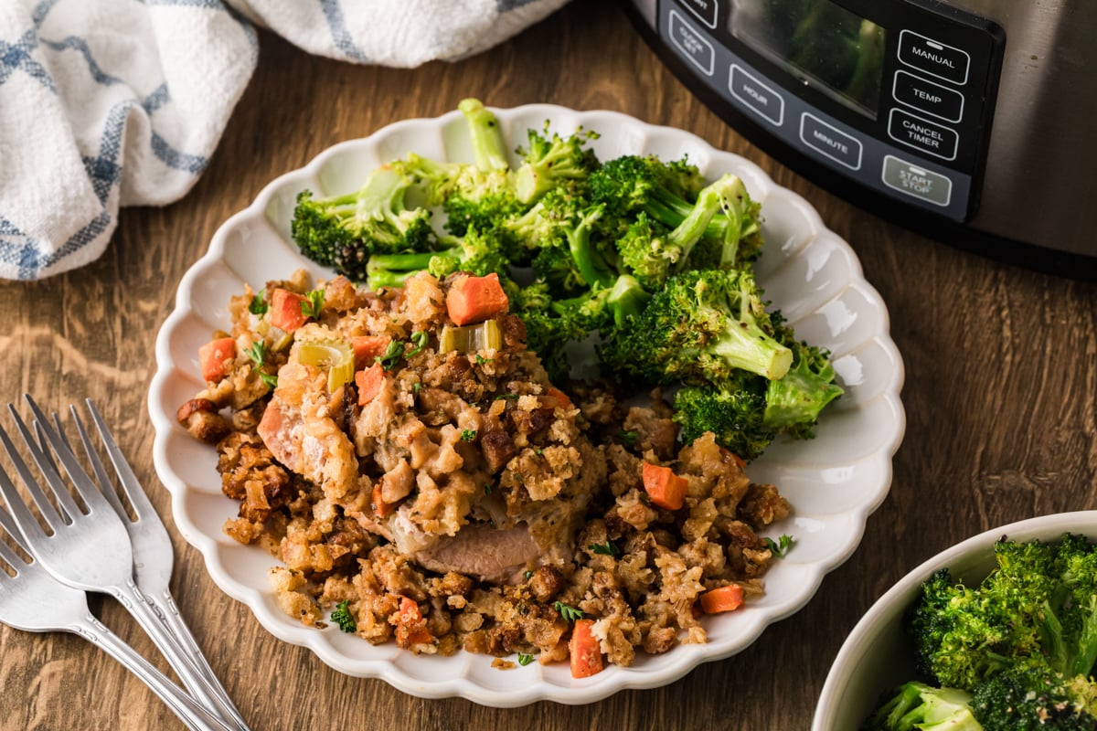 A serving of pork chops and stuffing with broccoli on a white plate.