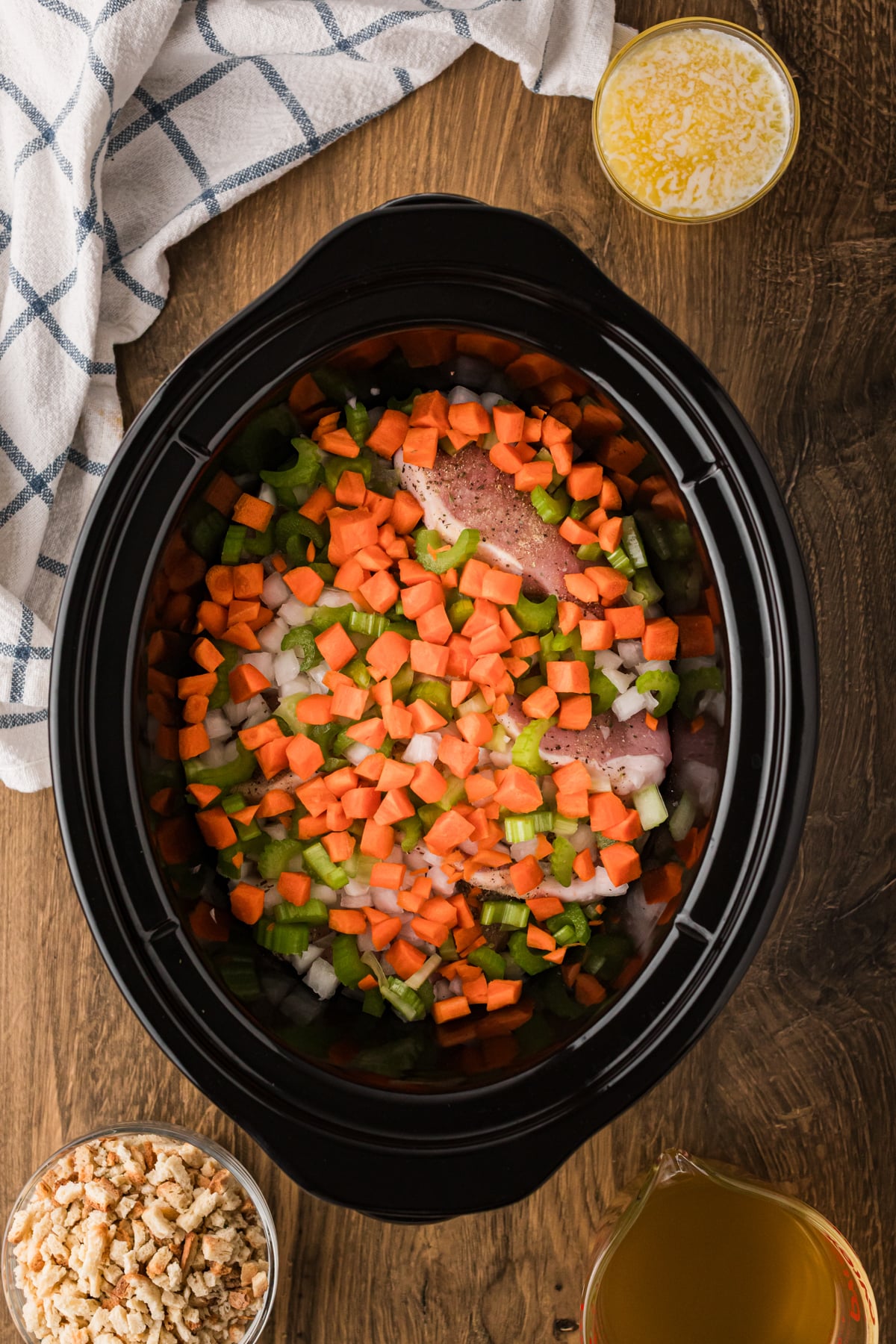 Carrots, celery, and onion on top of pork chops in a crockpot.
