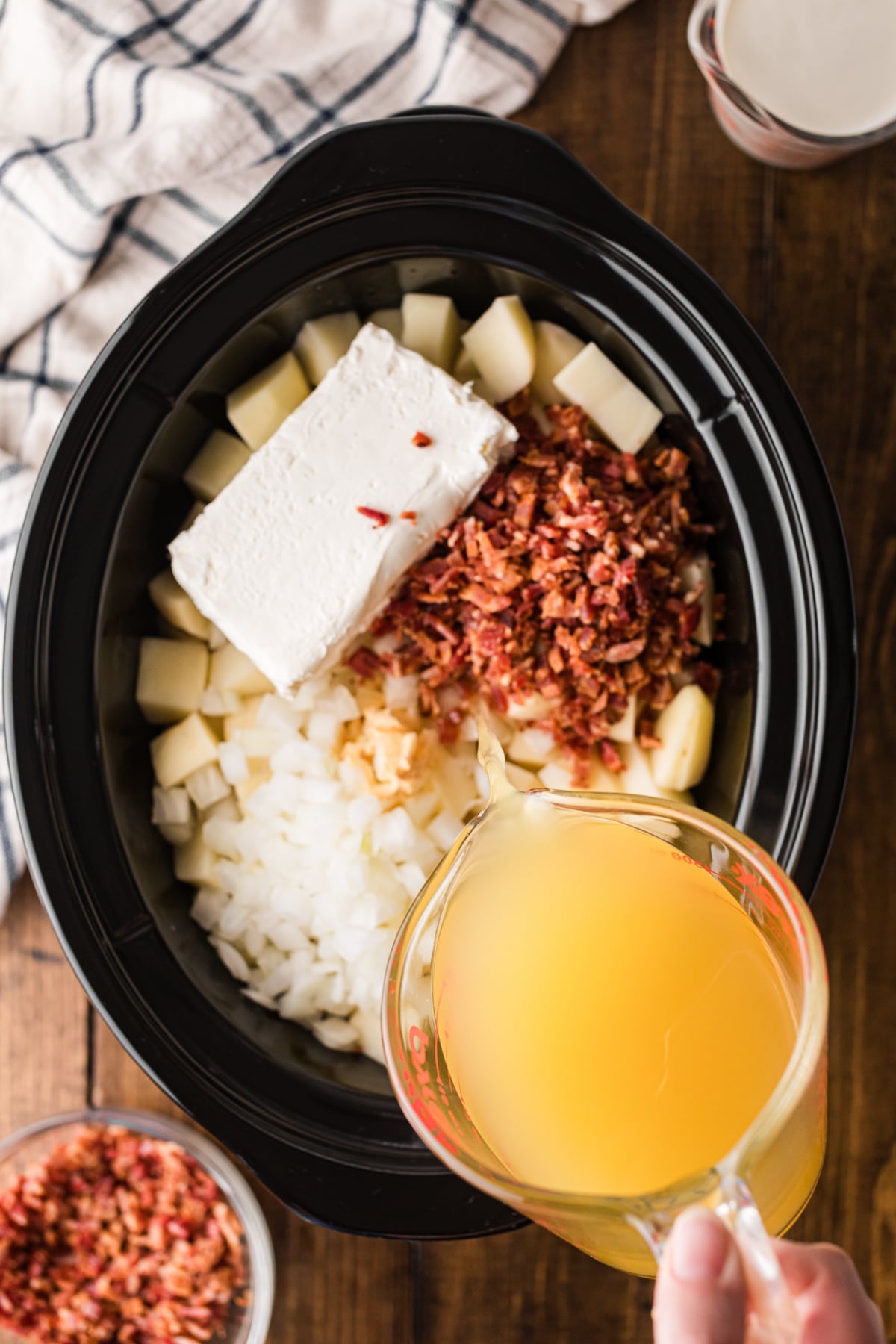 Pouring chicken broth into a crockpot.