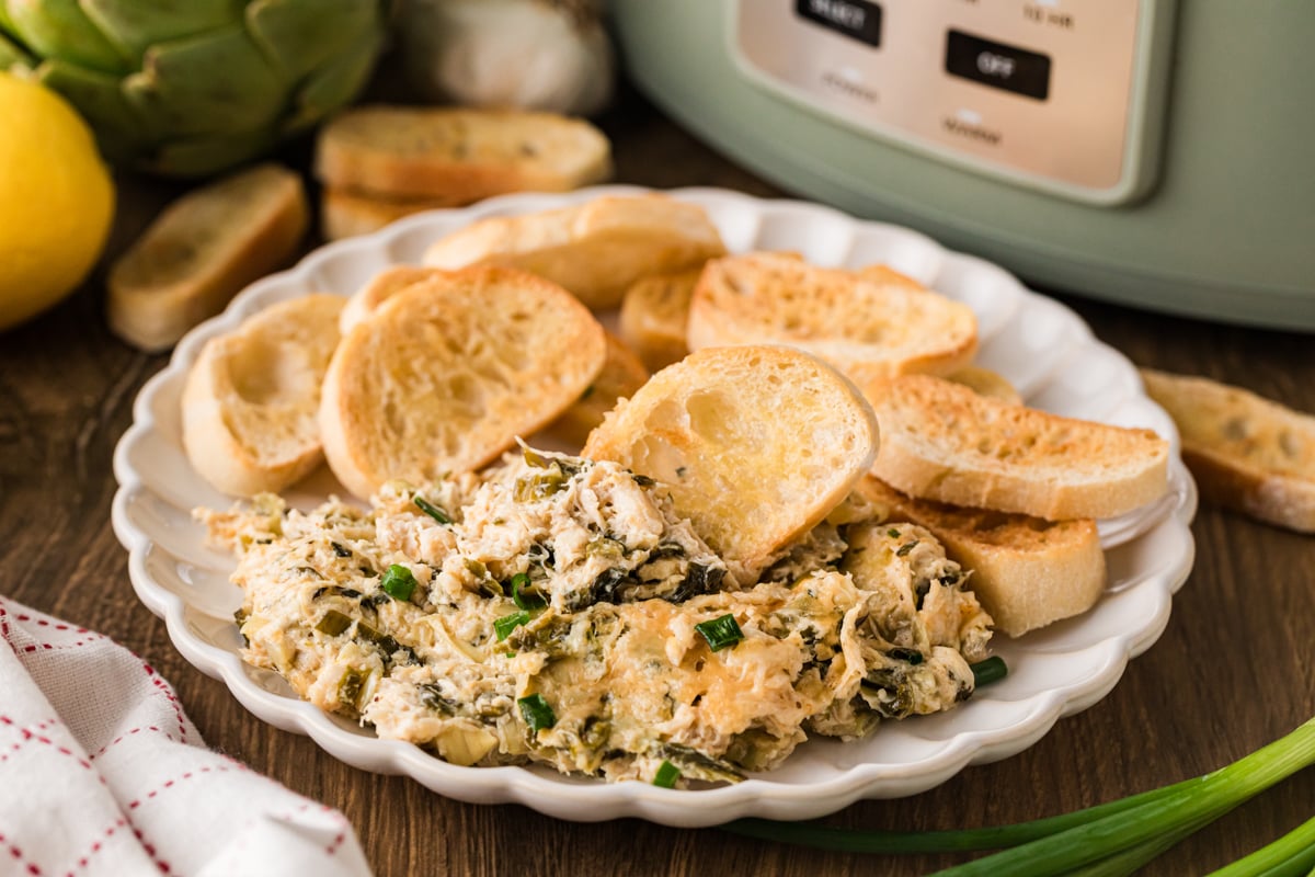 A whiter plate with a serving of crab dip and baguette slices.