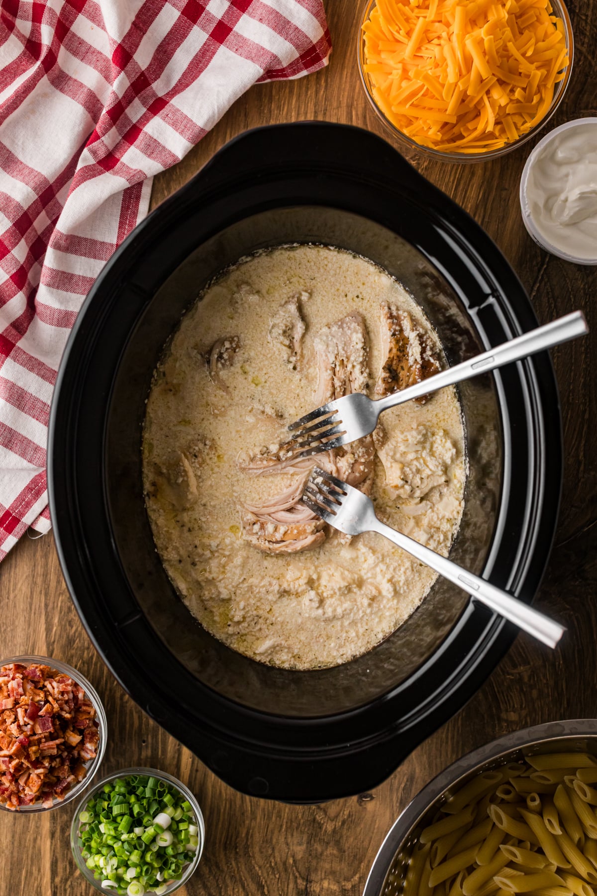 Shredding chicken in a crockpot with two forks.