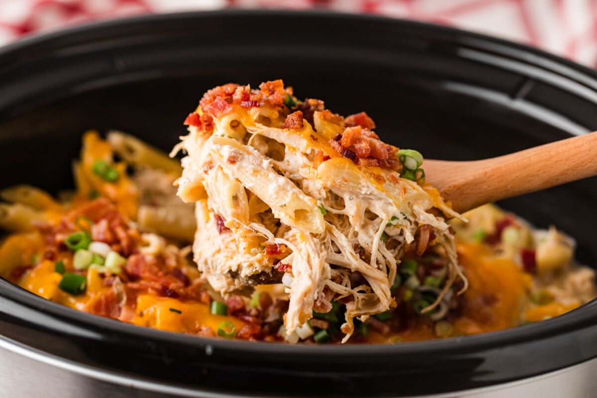 A scoop of crack chicken pasta coming out of a crockpot.