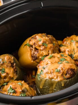 Taco stuffed peppers with melted cheese on top in a slow cooker.