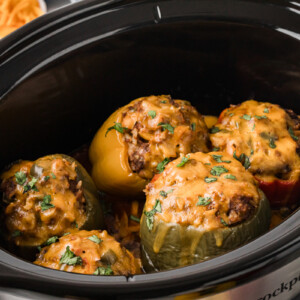 Taco stuffed peppers with melted cheese on top in a slow cooker.