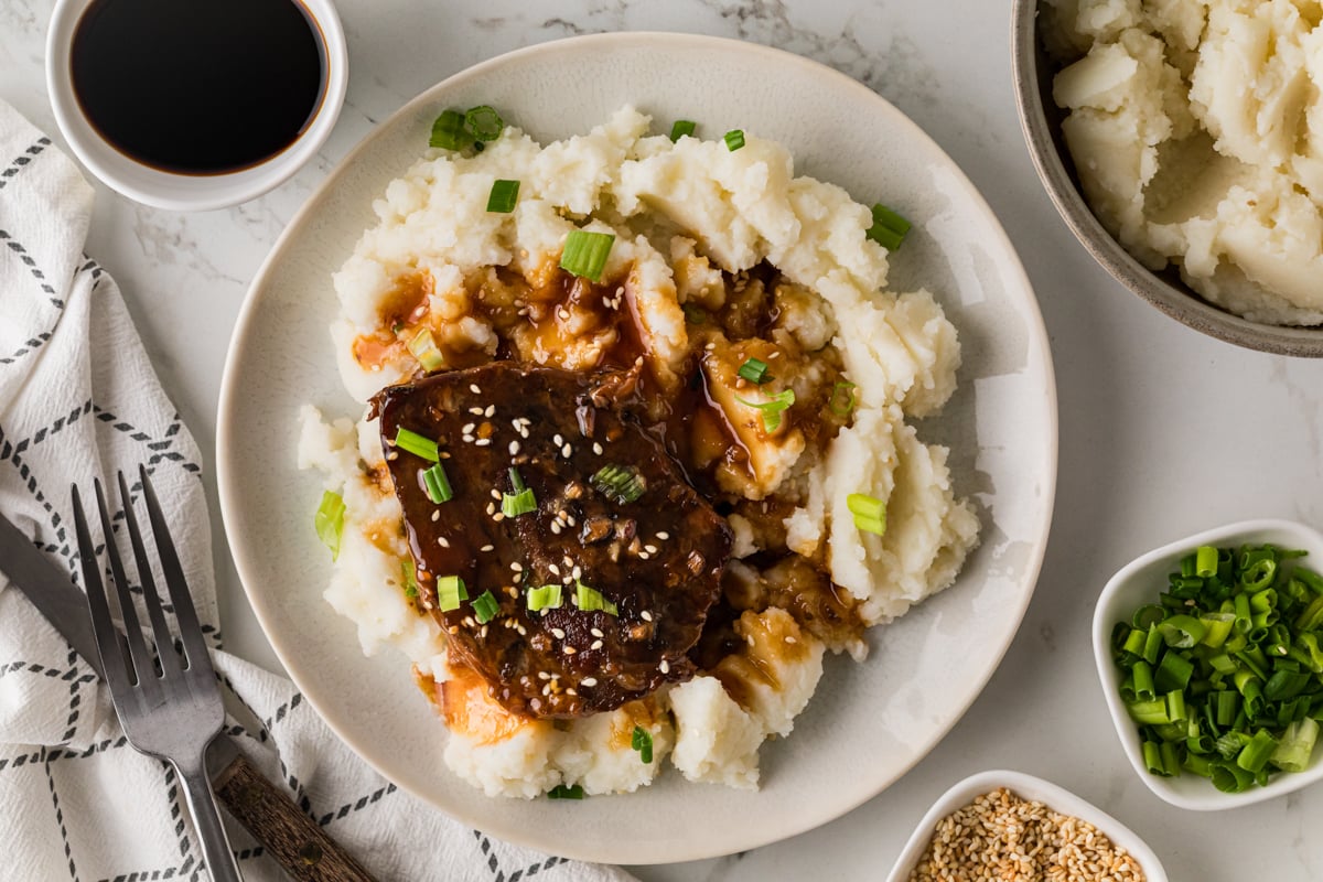 A serving of teriyaki steak with mashed potatoes on a plate.