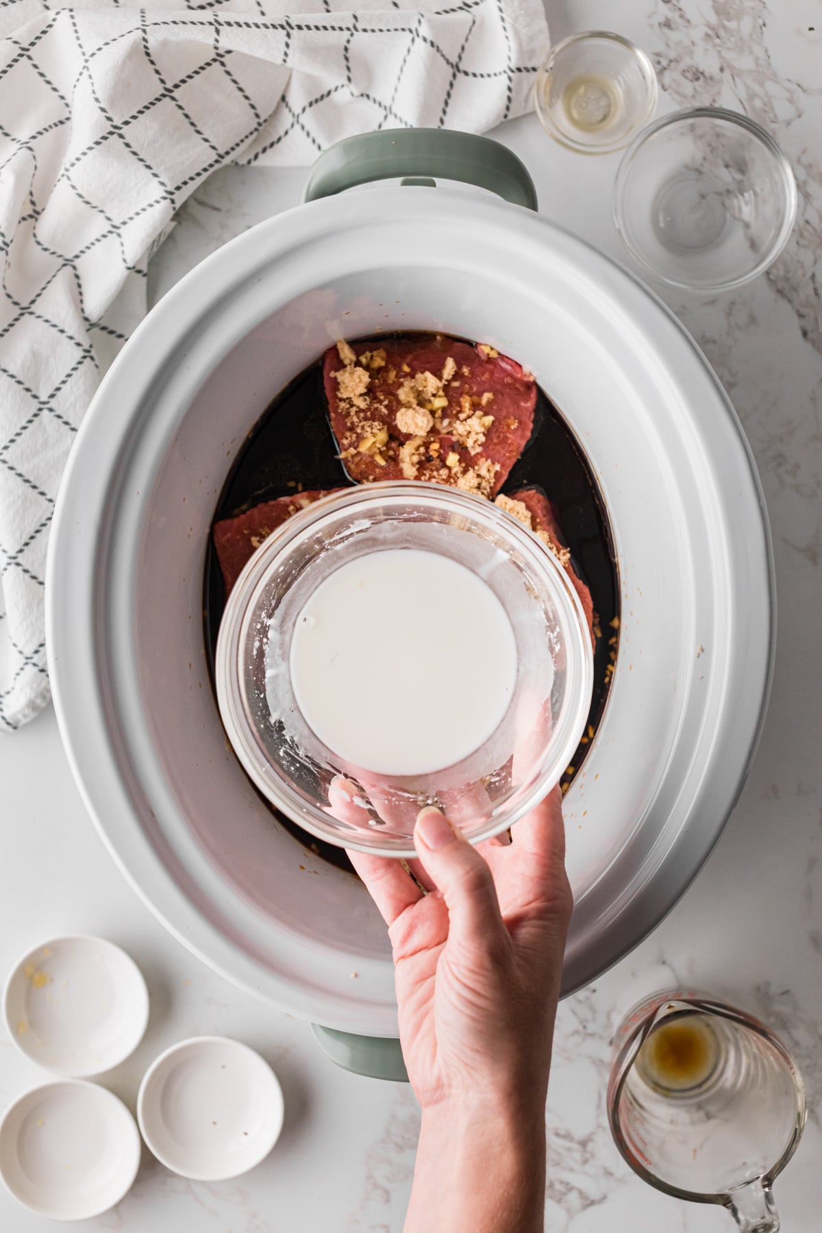 Holding a bowl filled with a cornstarch slurry over a crockpot.