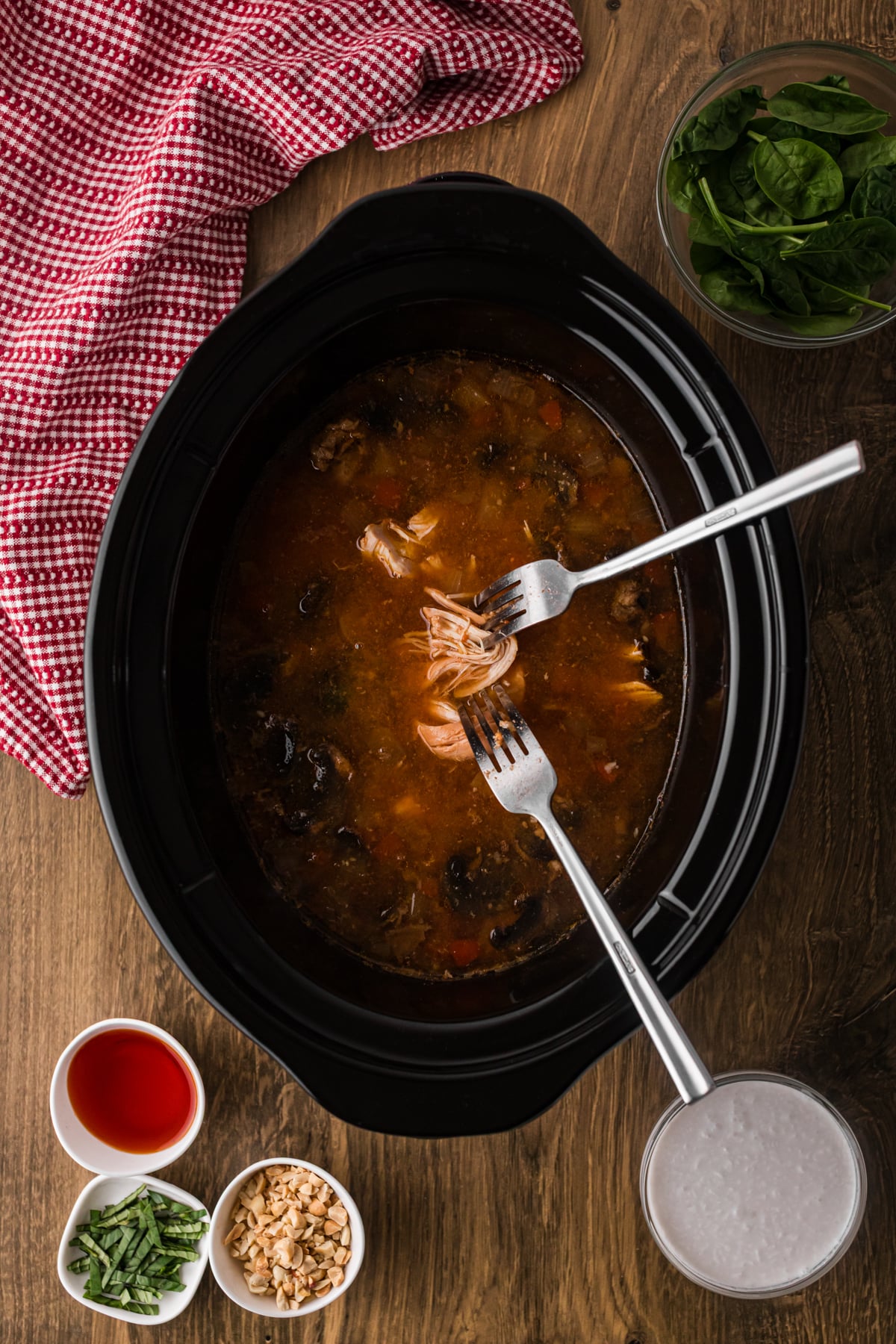 Shredding cooked chicken in a slow cooker using two forks.