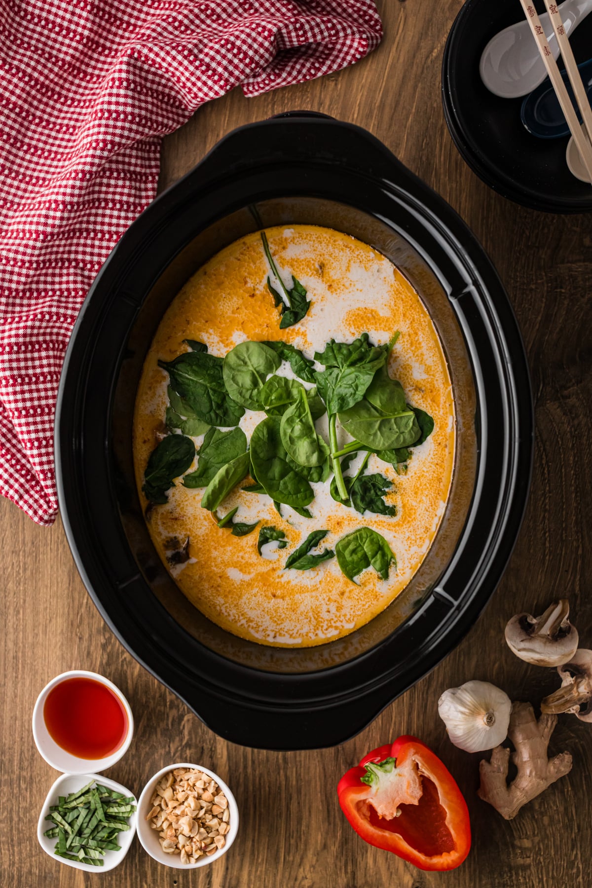 Coconut milk and spinach added to curry soup in a crockpot.