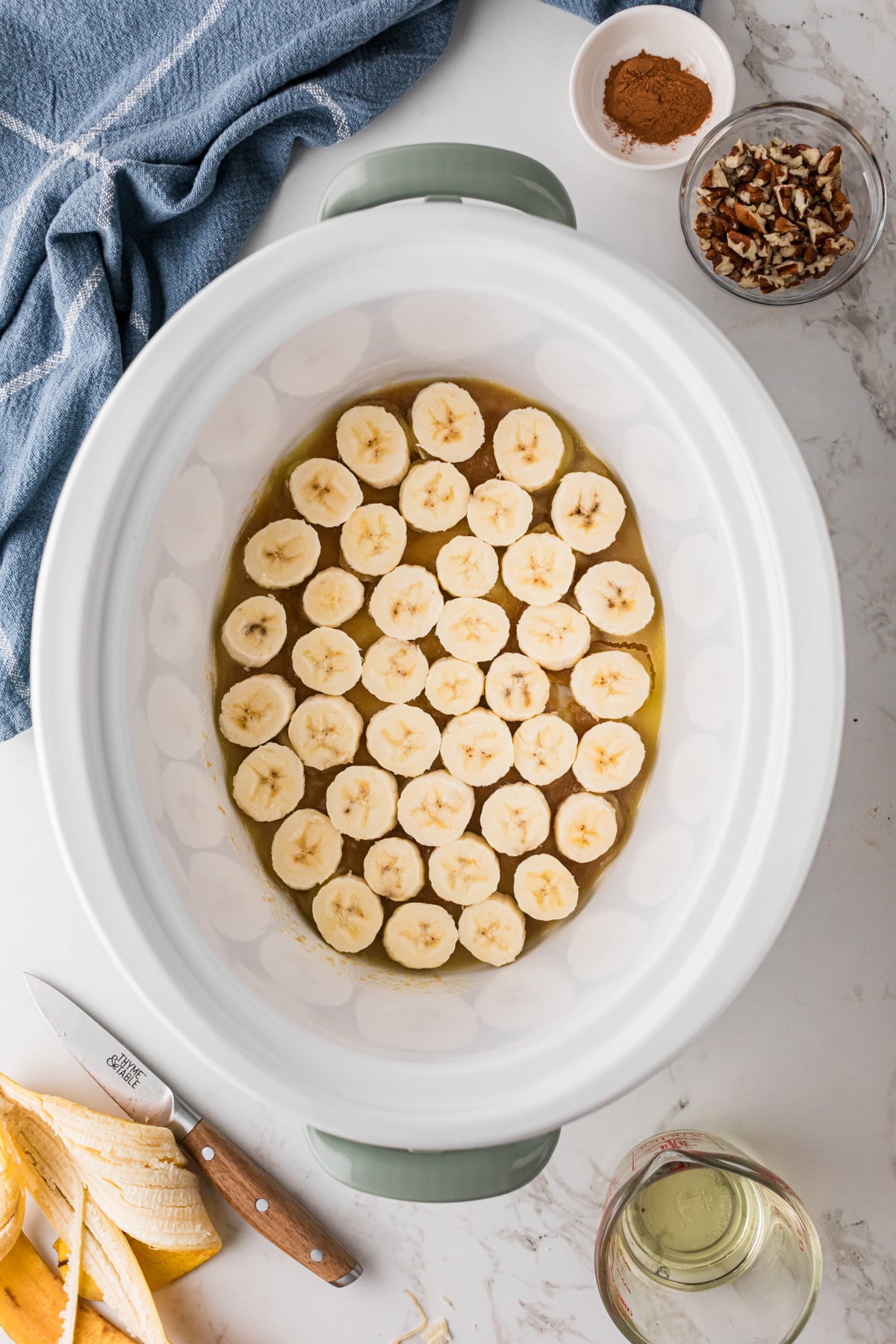 Sliced bananas layered onto butter-brown sugar mixture in a crockpot.