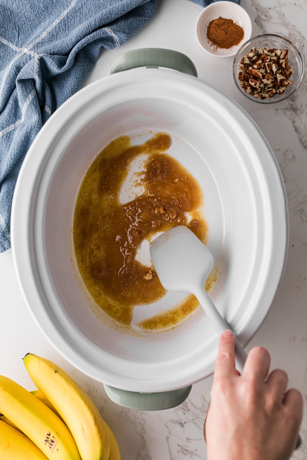 Stirring melted butter and brown sugar together in a crockpot.