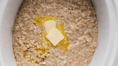 Oatmeal in a slow cooker with two pats of butter.