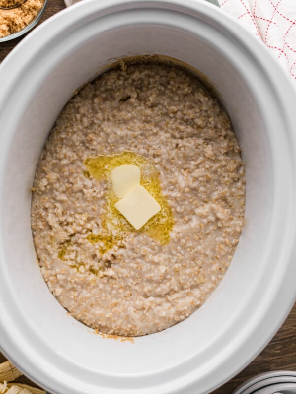 Oatmeal in a slow cooker with two pats of butter.