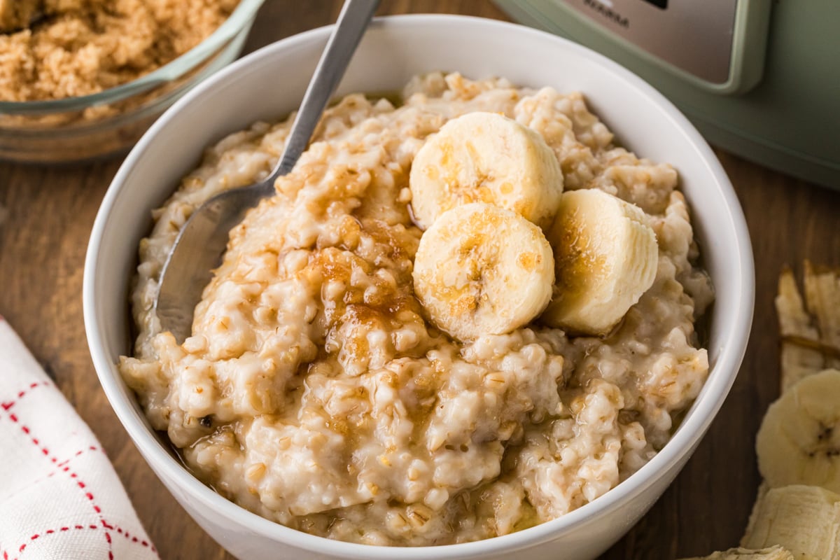 Close-up of oatmeal in a bowl with bananas and a spoon in it.