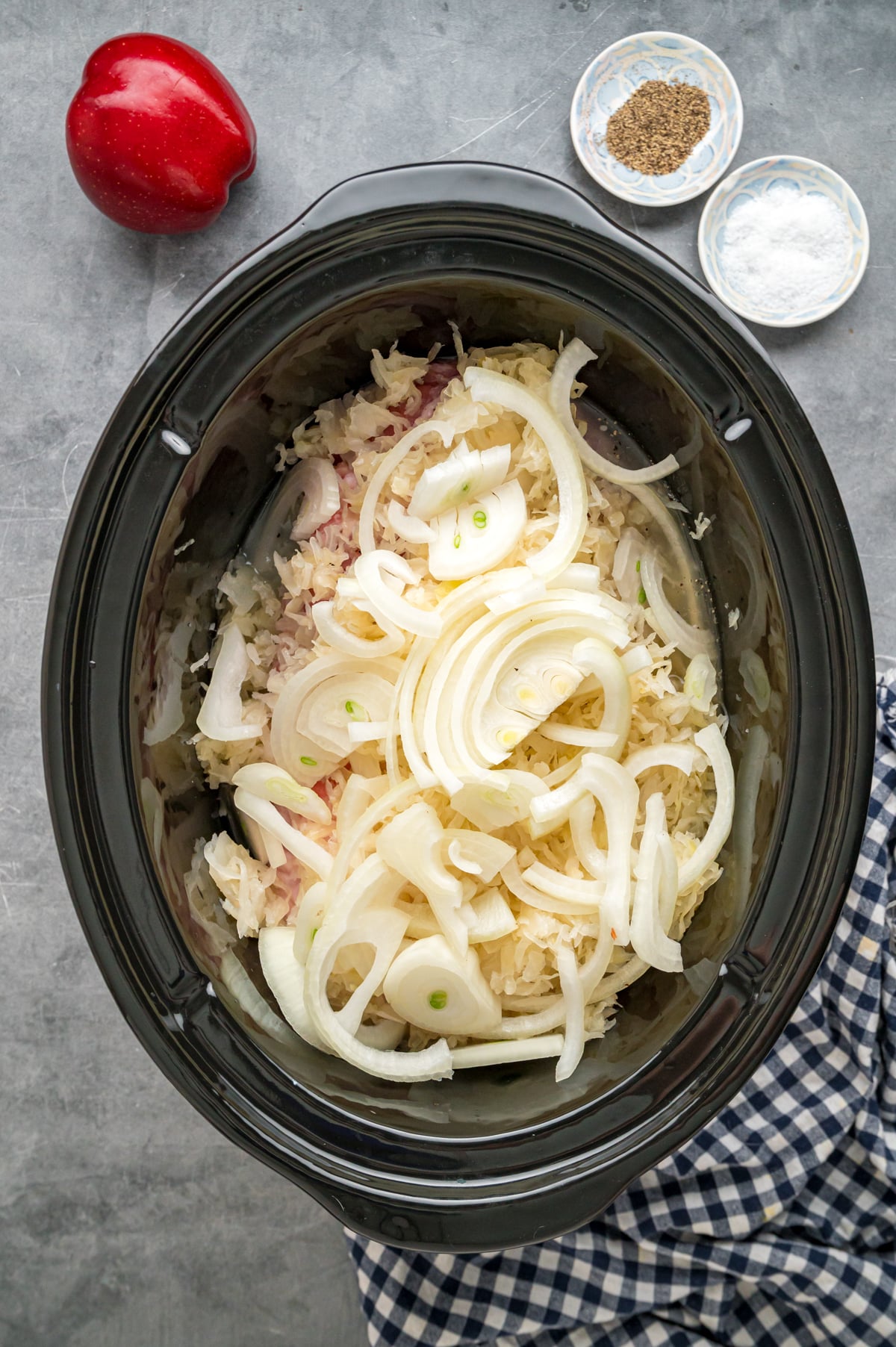 Pork loin with sauerkraut, apple cider vinegar, and sliced onion in a crockpot.