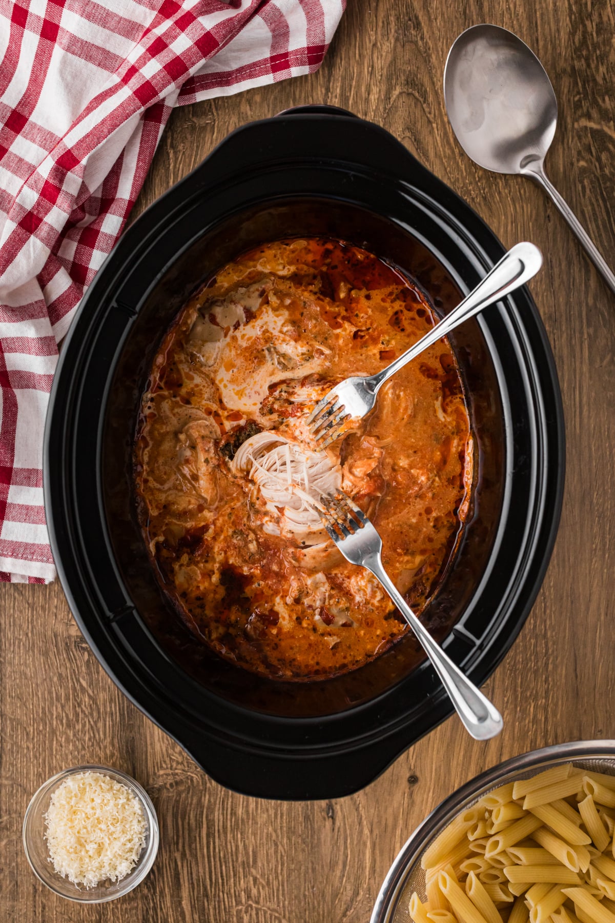 Shredding chicken in a crockpot with two forks.