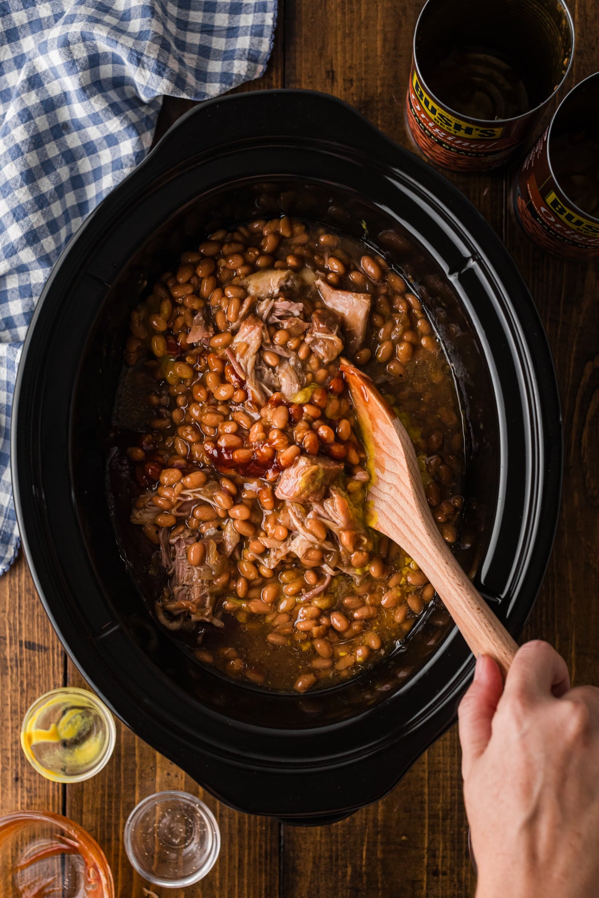 Stirring beans and pork together in a crockpot.