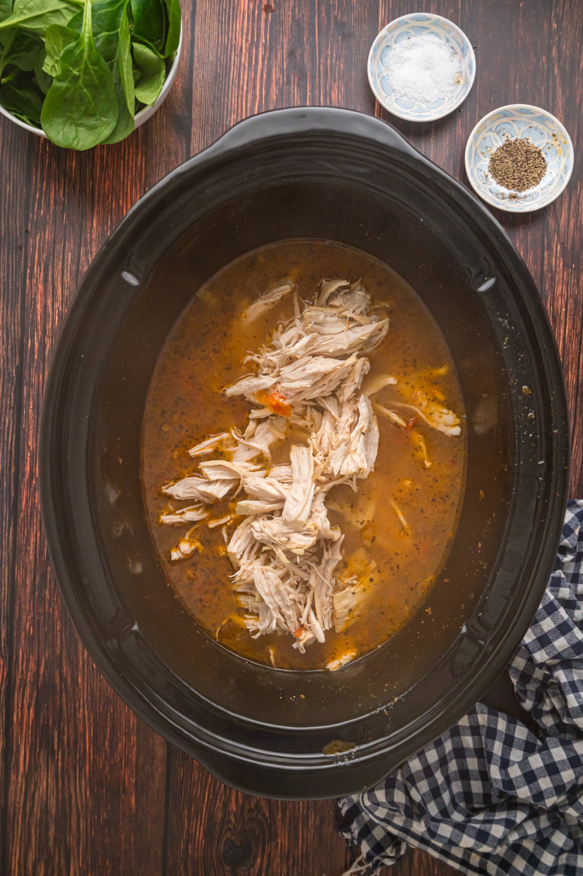 Shredded chicken in broth in a crockpot.
