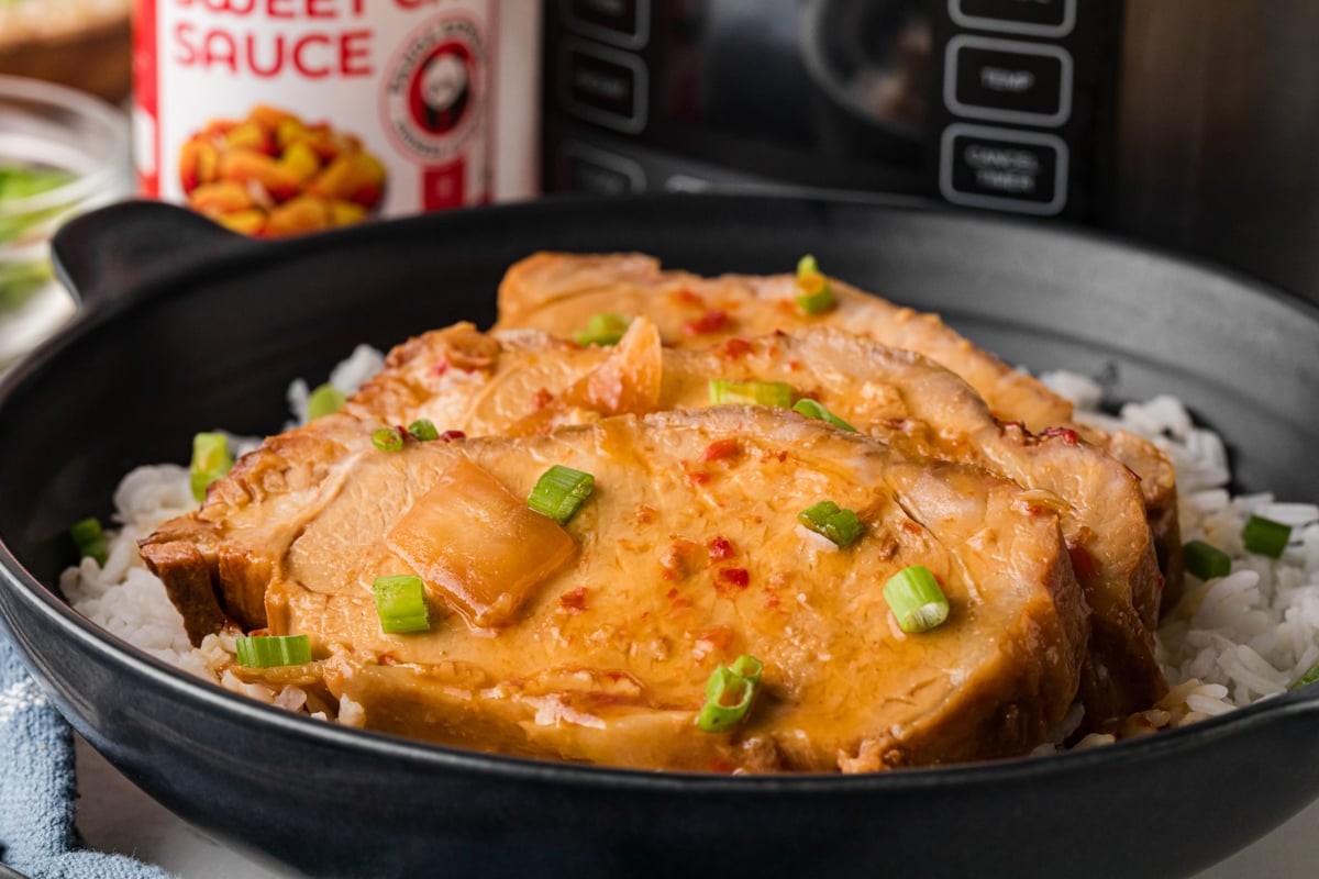 A serving of sweet chili pork over a bed of rice on a plate.