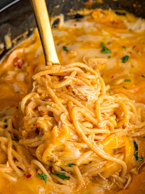 A big scoop of chicken taco spaghetti being pulled from a crockpot.