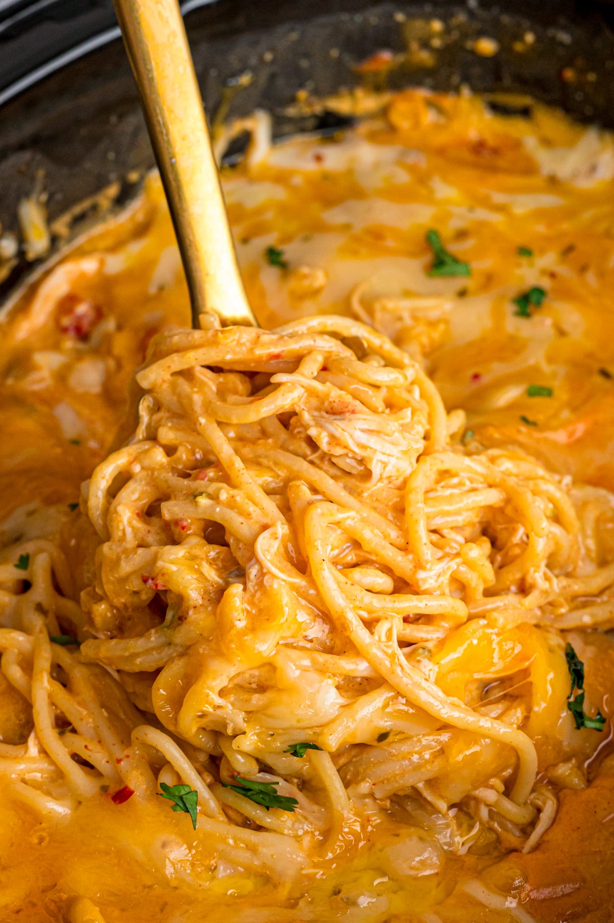 A big scoop of chicken taco spaghetti being pulled from a crockpot.