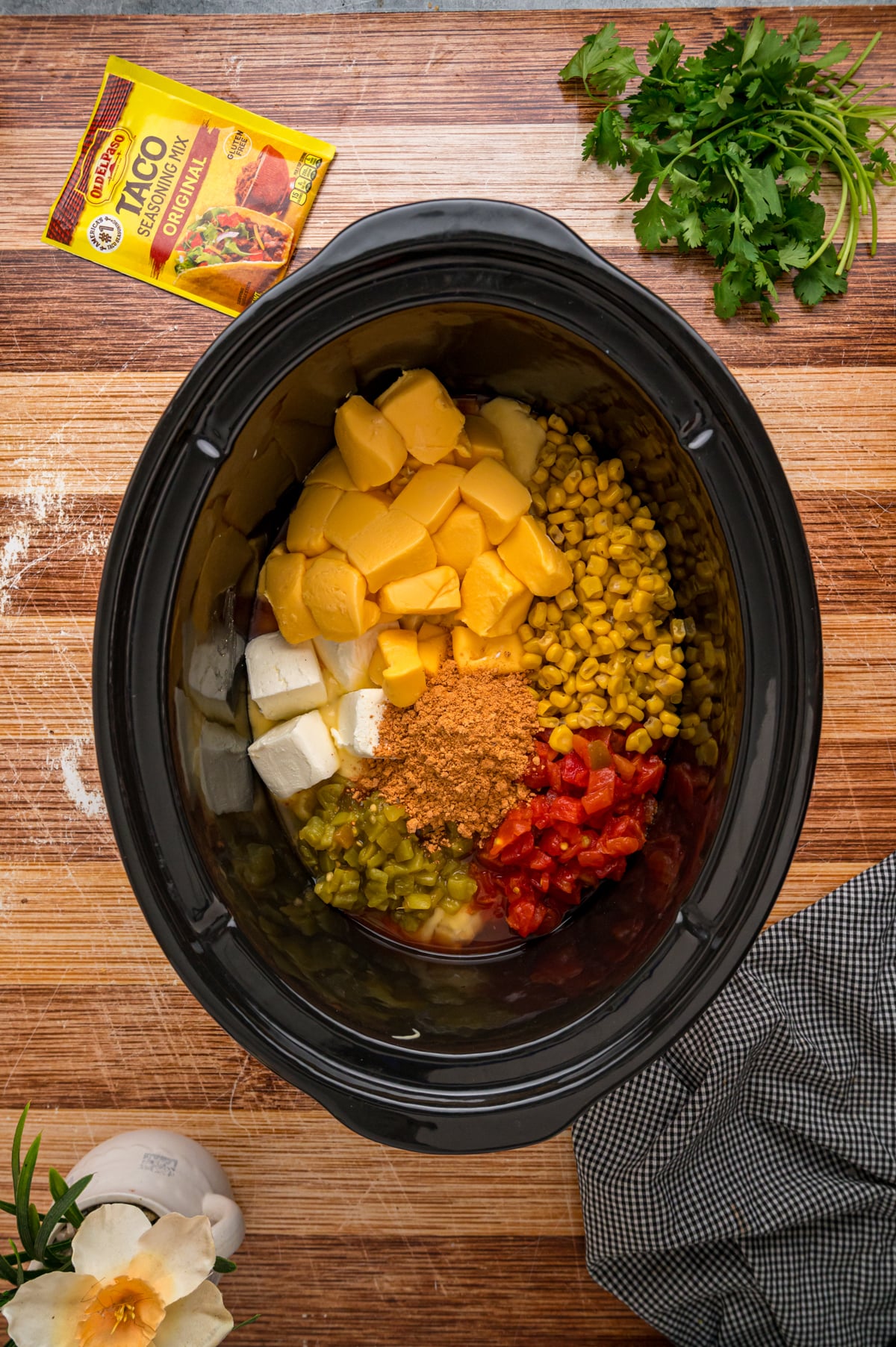 Cream of chicken soup, diced tomatoes, green chilies, corn, cream cheese, Velveeta, and taco seasoning in a crockpot.