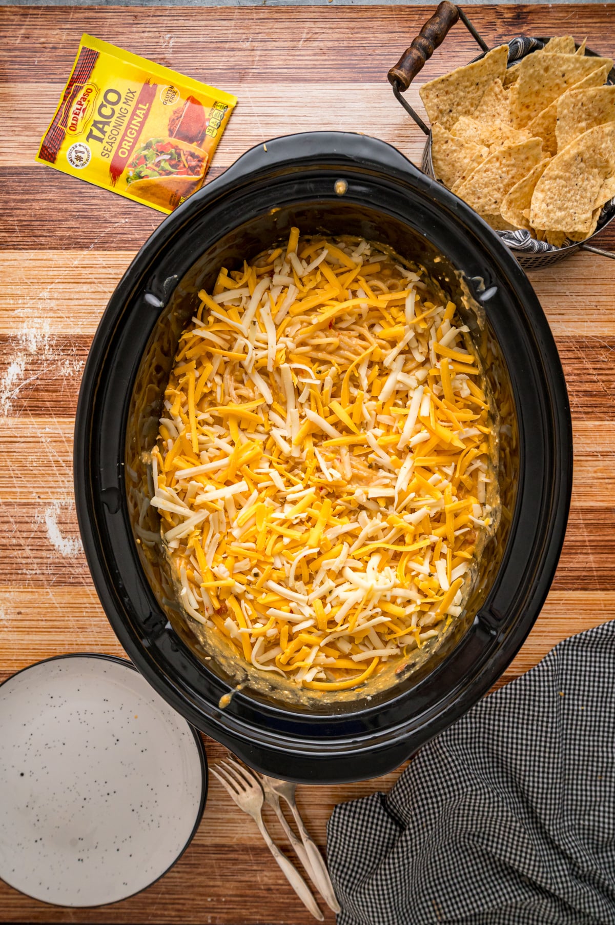 Shredded cheese on top of cooked chicken taco spaghetti in a crockpot.