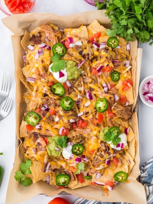Pulled pork nachos with toppings on a sheet pan.