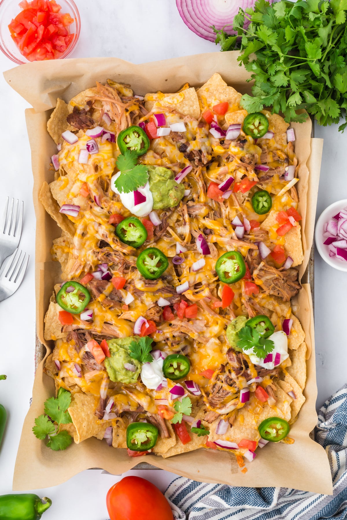 Pulled pork nachos with toppings on a sheet pan.