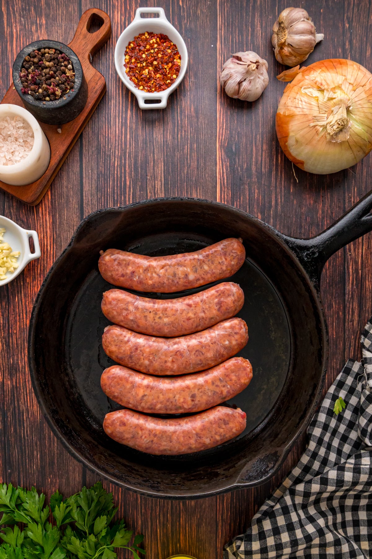 Five links of Italian sausage cooking in a skillet.
