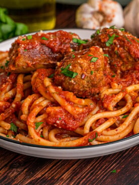 A dish of spaghetti topped with sausage and meatballs in tomato sauce.