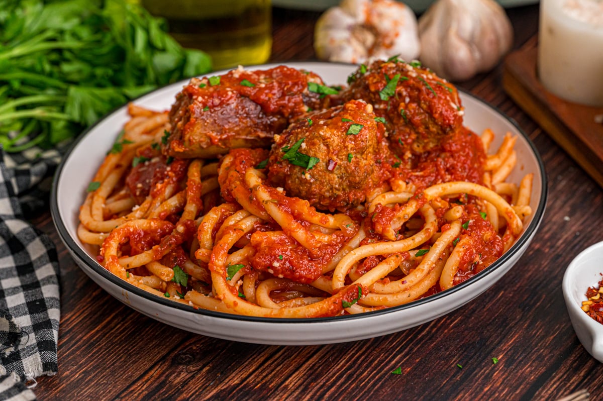 A dish of spaghetti topped with sausage and meatballs in tomato sauce.