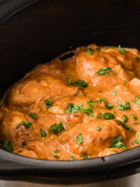 Cooked chicken thighs in a crockpot smothered in peanut sauce.